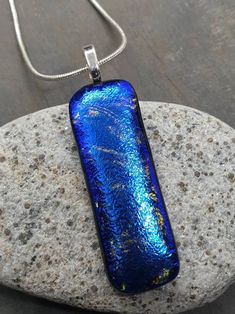 a blue pendant sitting on top of a rock