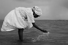 black and white photograph of a man in the ocean reaching for something with his hand