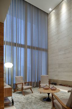 a living room filled with furniture next to a tall window covered in blue sheer curtains