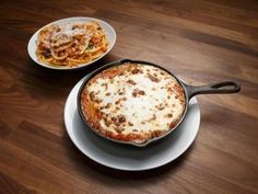 two plates with food on them sitting on top of a wooden table next to each other