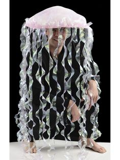 a man sitting on top of a white table under a pink jellyfish net covered in streamers