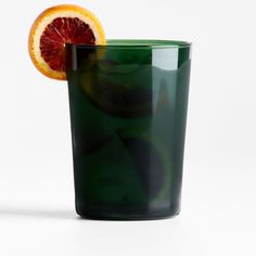 a green glass with an orange slice in it