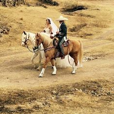 two people riding horses on a dirt road