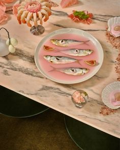 there is a plate with fish on it next to flowers and other items that are sitting on the table