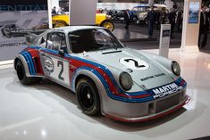 an old race car is on display in a showroom with people looking at it