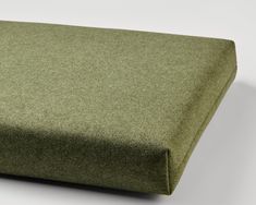 a close up view of a green cushion on a white surface with no one in it