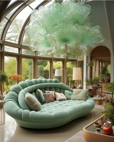 a living room filled with lots of furniture and large green flowers hanging from the ceiling