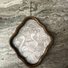 an ornate wooden frame hanging on a marble counter top with white lace in the center