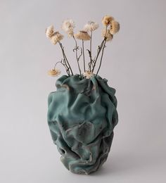 a vase with flowers in it sitting on a table next to a white wall and gray background