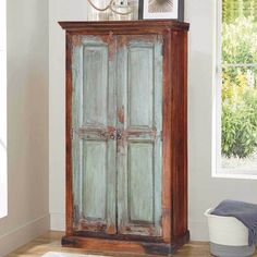 an old wooden armoire sitting in a room next to a rug and pictures on the wall