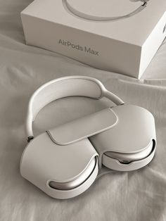 a pair of white headphones sitting on top of a bed next to a box