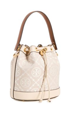 PRICES MAY VARY. Fabric: Jacquard Structured silhouette, Gold-tone hardware, Monogram pattern, Leather trim Length: 8.25in / 21cm, Height: 8.25in / 21cm, Handle drop: 4in / 10cm, Strap drop: 21.75in / 55cm, Depth: 4.75in / 12cm Drawstring top Patch interior pocket A scaled-down Tory Burch bucket bag, detailed with a rendition of the label's monogram for a polished and eye-catching look. Two shades of leather trim lend an eclectic finish to the silhouette. Tory Burch Bucket Bag, T Monogram, Mini Bucket Bags, Mini Bucket, Monogram Pattern, Drawstring Top, Tory Burch Bag, Color Ivory, Leather Trim