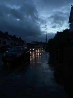 cars are parked on the side of the road in the rain at night with street lights shining