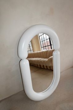 a mirror that is sitting on the ground in front of a wall with a couch behind it