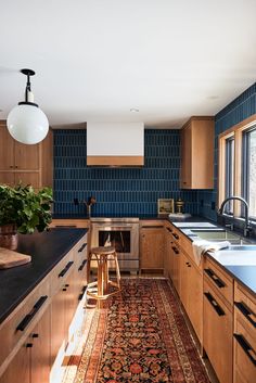 a kitchen with wooden cabinets and blue tile backsplash, an area rug on the floor