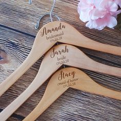 three wooden spoons with names on them sitting next to some pink carnations