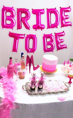 the bride to be balloon sign is displayed on a table with pink decorations and cake