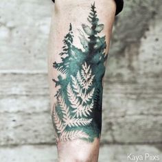 a person with a tattoo on their leg that has trees and leaves painted on it