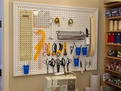 a peg board with scissors and other crafting supplies hanging on it's wall