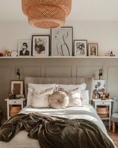 a bed with pillows, blankets and pictures on the wall above it's headboard