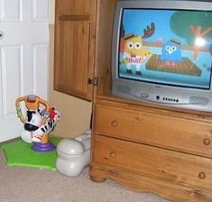 an old tv sitting on top of a wooden dresser next to a toy cow and other toys