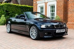 a black bmw convertible parked in front of a brick building