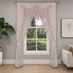 a living room with a couch, chair and window covered in pink sheer curtaines