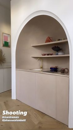 an arch in the wall with shelves above it and bowls on the counter top below