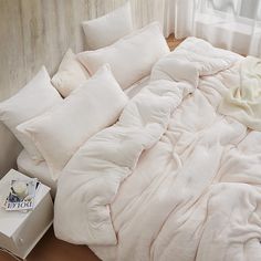 an unmade bed with white pillows and blankets