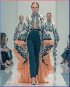 a model walks down the runway in an orange and blue outfit