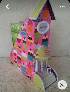 a paper doll house with cupcakes on the front and sides, sitting on a table