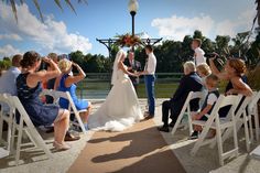 a bride and groom standing at the end of their wedding ceremony with guests sitting on white chairs