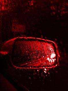 the side view mirror of a car with red light on it's side window