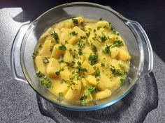 a glass bowl filled with food sitting on top of a gray countertop next to a black table