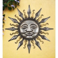 a metal sun face on a yellow wall