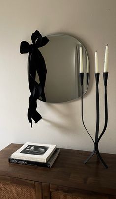 a table with a mirror and two candles sitting on top of it next to a book