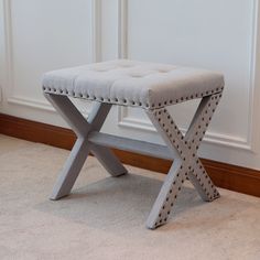 a gray bench sitting on top of a carpeted floor next to a white wall