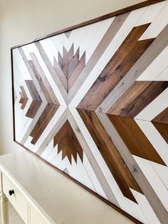 a large wooden wall hanging on the side of a white wall next to a window