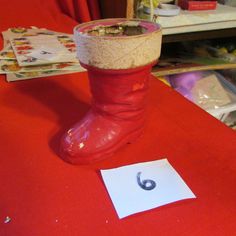 a pair of red boots sitting on top of a table next to a piece of paper