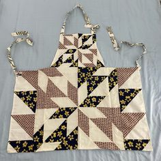 two aprons that are sitting on top of a table together, one is made out of fabric and the other has an interesting design