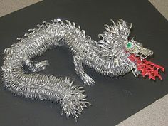 a metal dragon statue sitting on top of a black table next to a red object