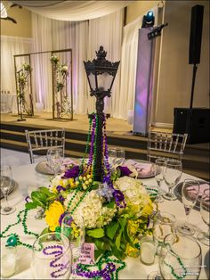 a table set up for a mardi gras party with beads and flowers on it