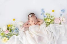 a baby is laying down with flowers around her