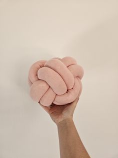 a hand holding up a pink knot cushion