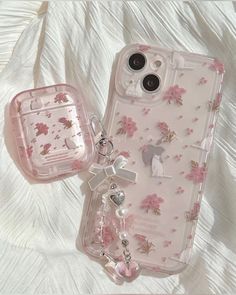 two cell phones are laying next to each other on a white sheet with pink flowers