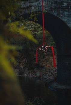 a man hanging upside down from a red rope