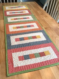 a table runner made from strips of fabric on top of a wooden dining room table