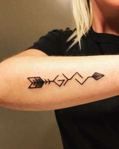 a woman's arm with an arrow tattoo on the left side of her arm