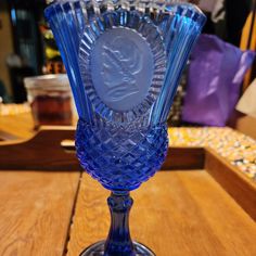 a blue glass vase sitting on top of a wooden table