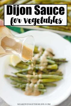 a person pouring sauce on asparagus with the words dijon sauce for vegetables